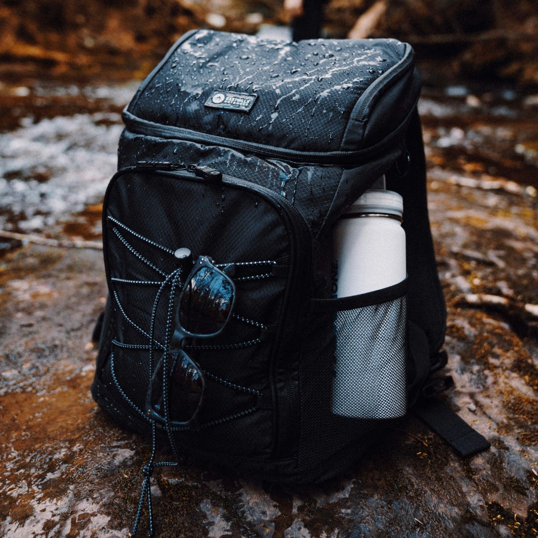 sac à dos isotherme noir sur un rocher en forêt sous la pluie